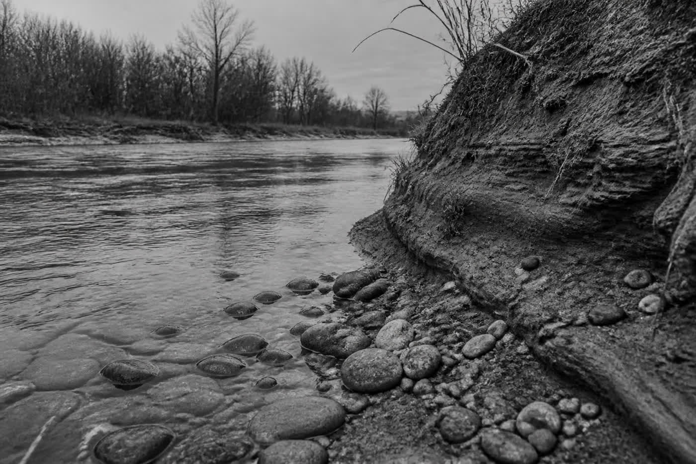 Black-and-white riverbank of layered silt and stones