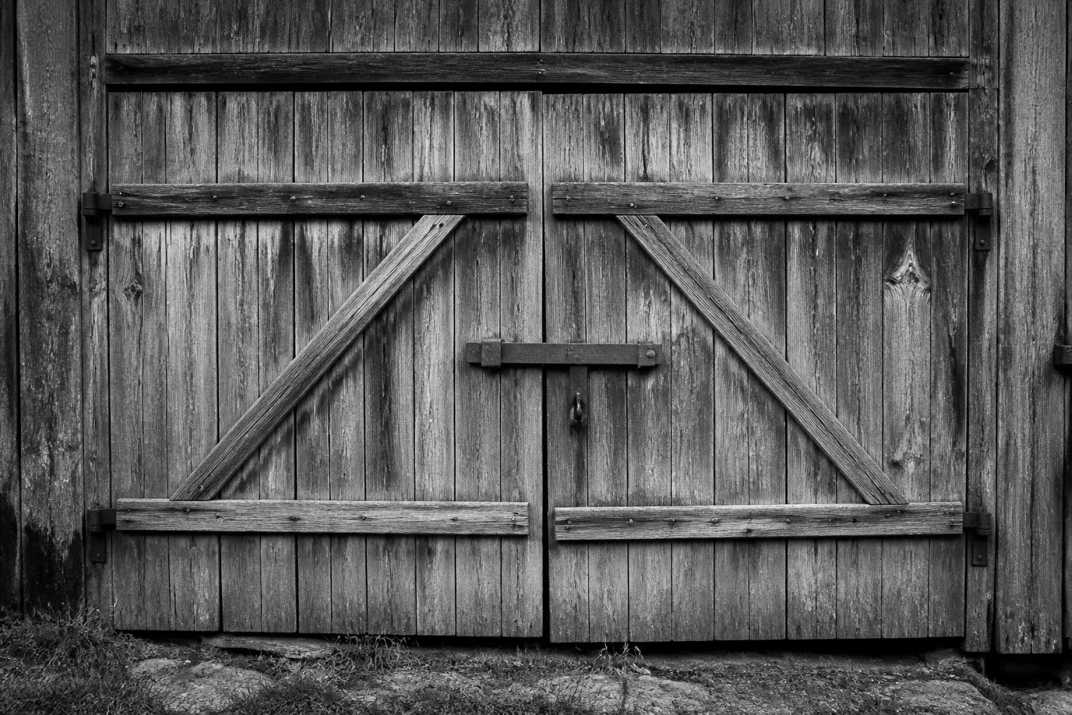 Black-and-white closed weathered barn doors with a latch
