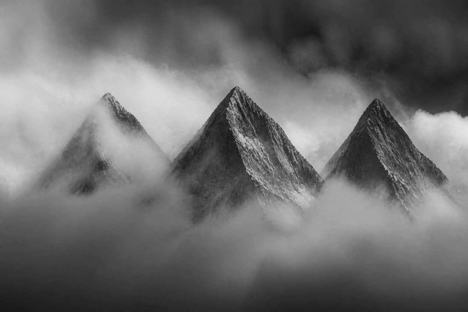 Black-and-white three mountain peaks in mist, slightly different heights
